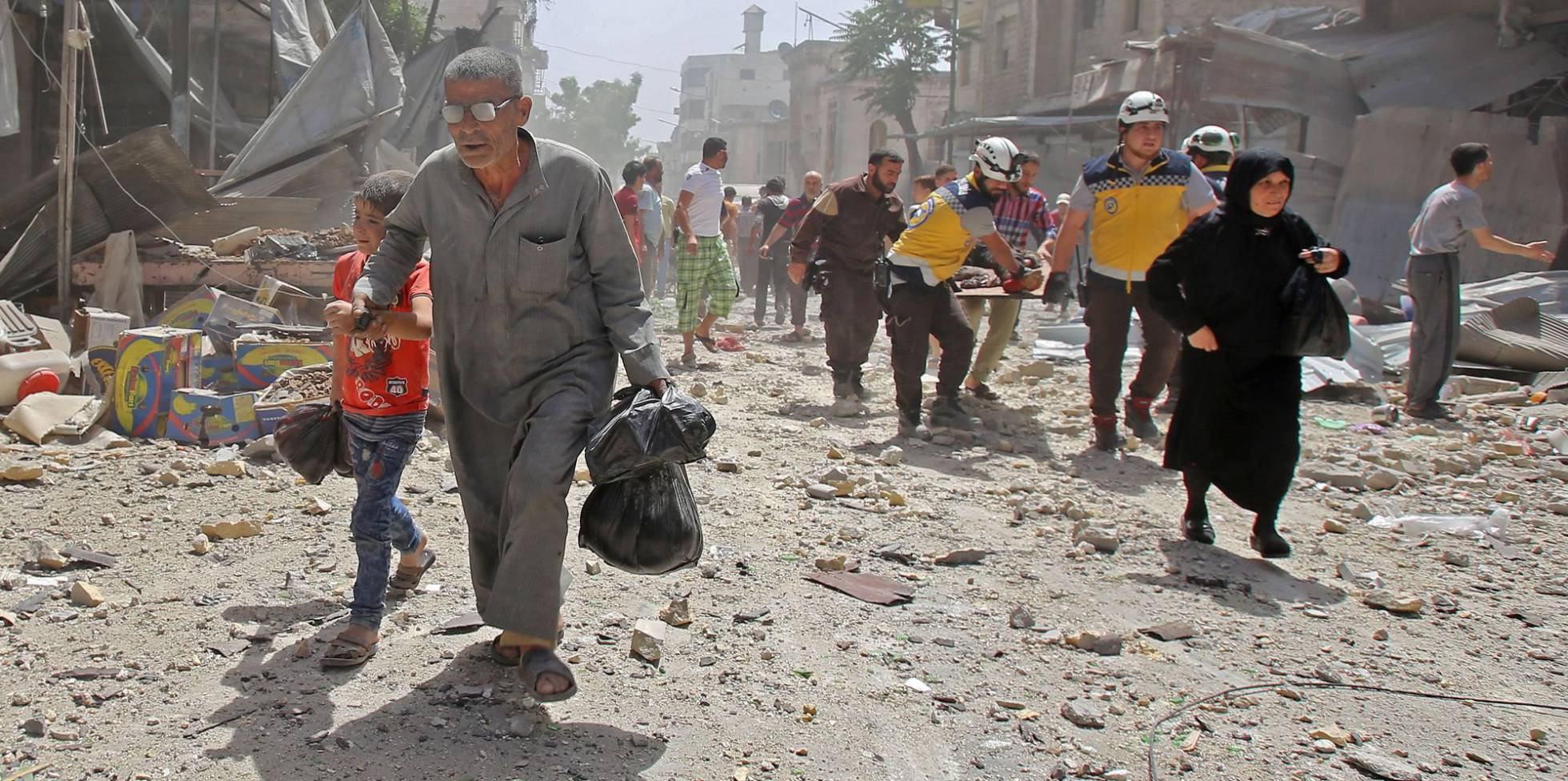 Un grupo de voluntarios de los 'cascos blancos' llevan a un hombre herido en camilla tras un ataque aéreo en la ciudad de Maaret al-Numan, en la provincia de Idlib (Siria).