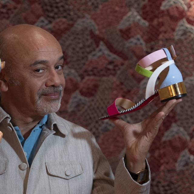 El diseñador Christian Louboutin, con dos de los zapatos que se venden en su nueva tienda de Barcelona.