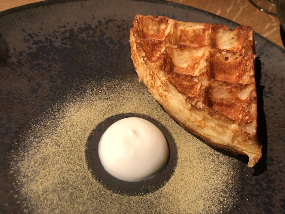Gofre caliente de harina de maíz relleno de queso raclette rodeado de un polvo verde de pepino encurtido y deshidratado, con una bola de yogur espeso Capel