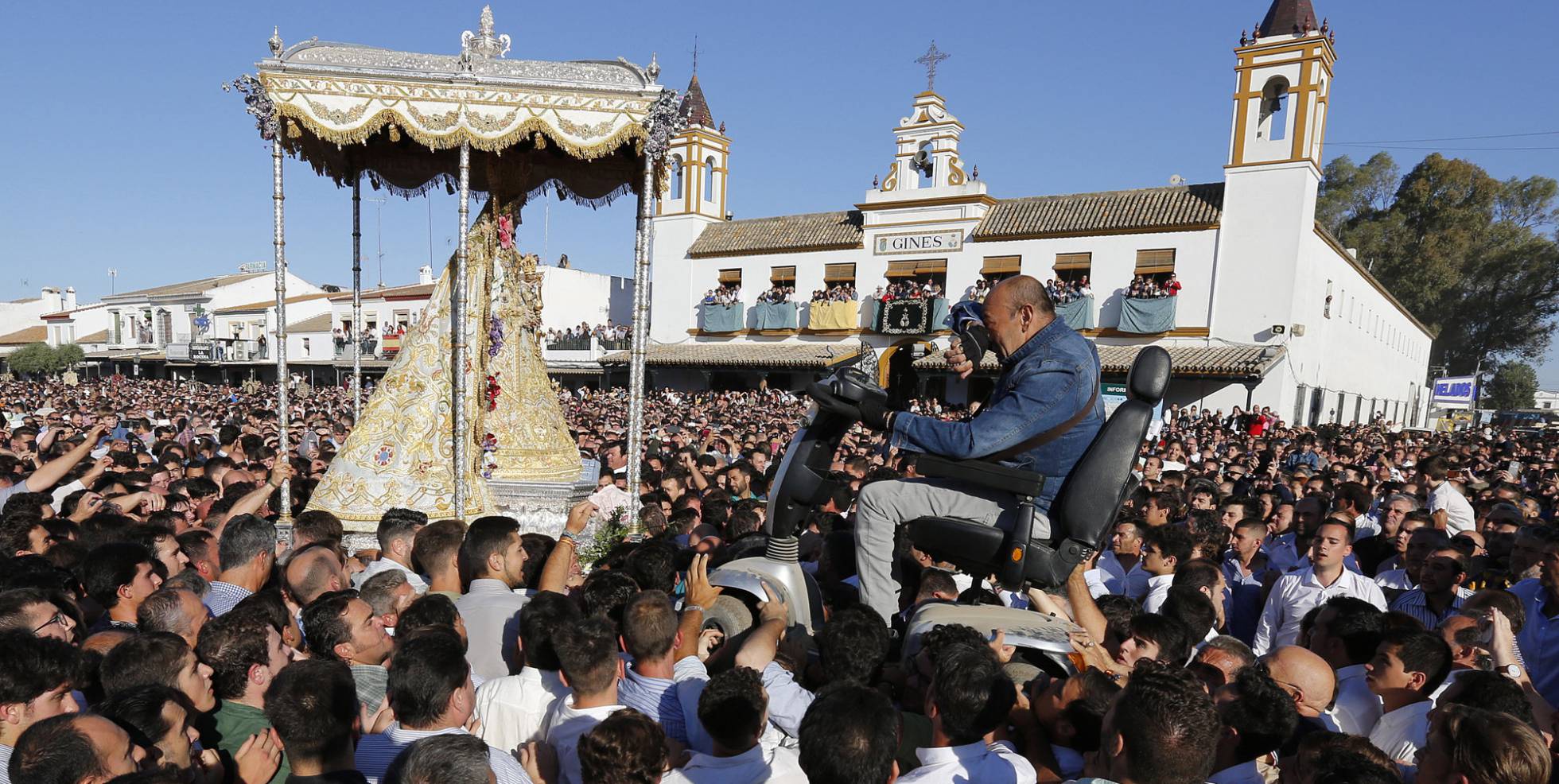 Un peregrino en una silla de ruedas motorizada es alzado por la multitud para poder aproximarse a la virgen del Rocío, en Almonte, Huelva (España).