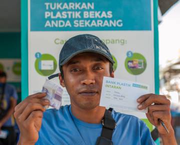 Un hombre muestra el dinero que ha conseguido a cambio del reciclaje de plástico en Naga (Filipinas).
