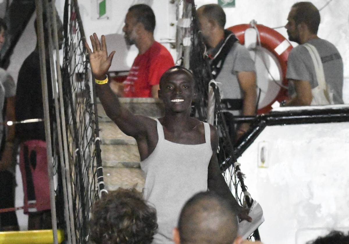 Un migrante saluda tras bajar del 'Open Arms' en el puerto de la isla de Lampedusa, esta madrugada.