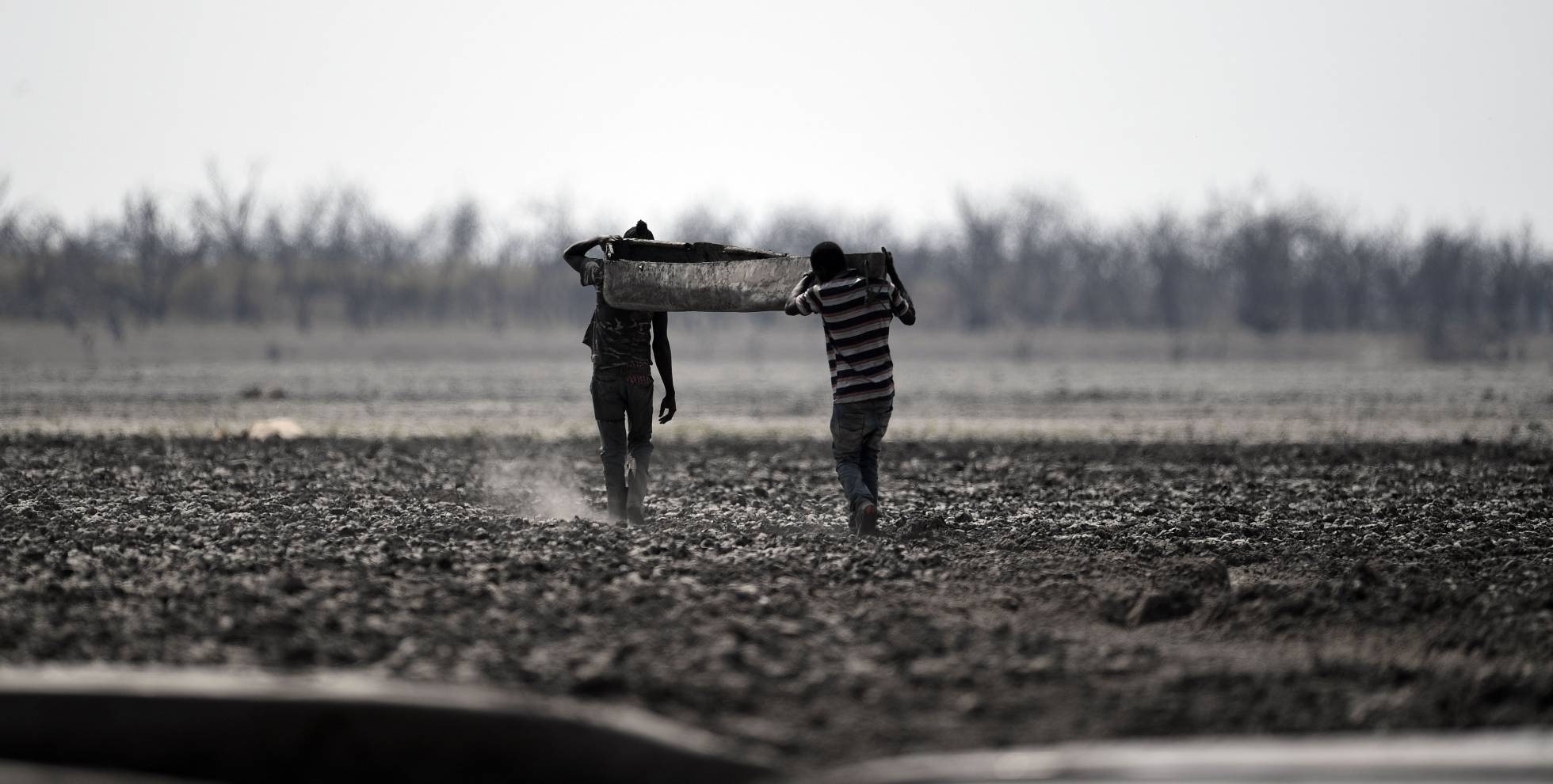 Pescadores cargan un bote por el lodo del lago Ngami, en Maun (Botsuana).