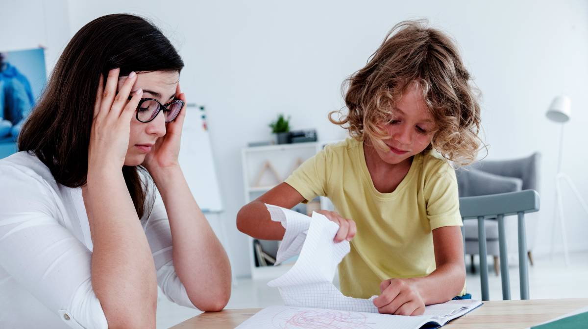 Un niño rompe una página de un cuaderno.