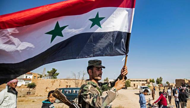 Un soldado ondea una bandera de Siria.