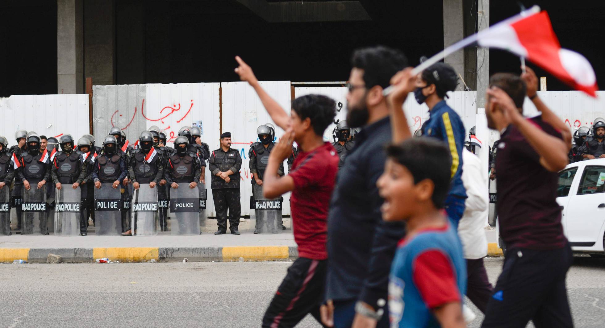 Manifestantes iraquíes marchan frente a fuerzas antidisturbios, en la ciudad iraquí de Najaf.