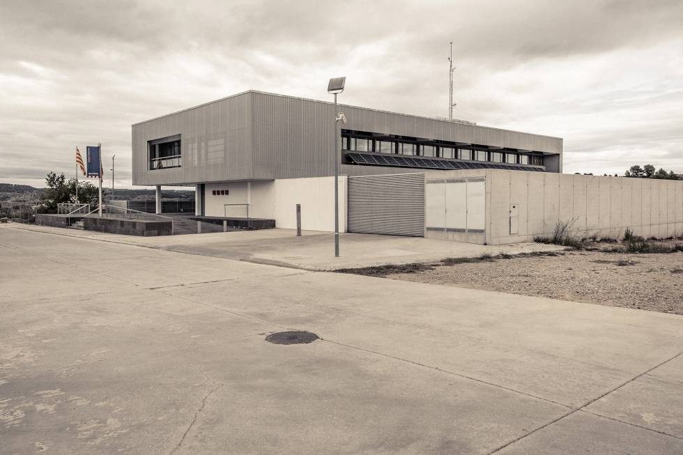“El edificio de la comisaría era un cubo flamante de dos pisos, de grandes paredes grises interrumpidas por grandes ventanales, que se levantaba en medio de un descampado, ya en el extrarradio de Gandesa”.