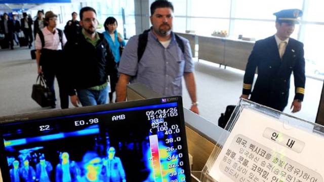Unos viajeros pasan por un control de temperatura.
