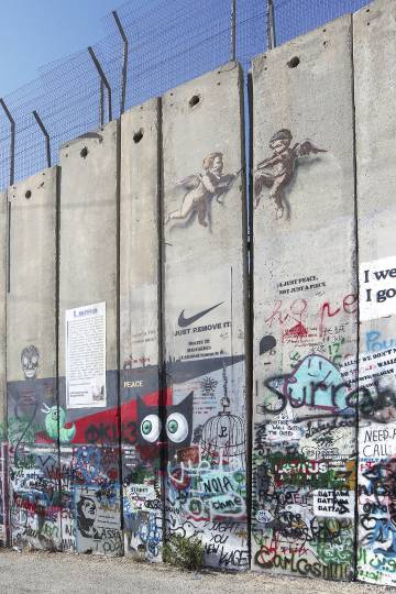 Dos ángeles de Banksy intentan abrir el muro.