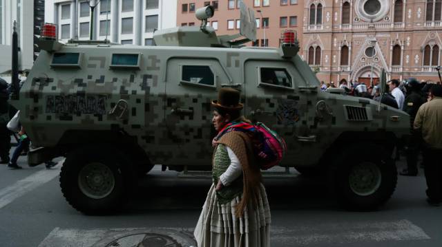 Una mujer camina frente a una tanqueta en el centro de La Paz.