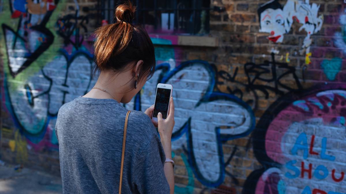 Una joven fotografía un grafiti en Brick Lane, Londres.