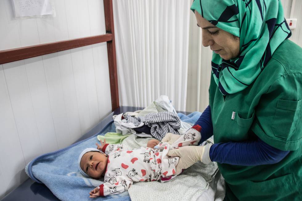 Una matrona atiende a un bebé en un hospital en un campo de refugiados al norte de Irak.