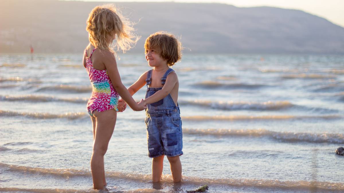 Dos niños juegan en la orilla del mar.