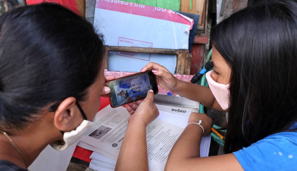 Christine Mae Escobido (derecha), de 11 años, y su madre Warlyn Langit estudian Geografía con la ayuda de un móvil en el barrio de Santa Ana, en Manila.