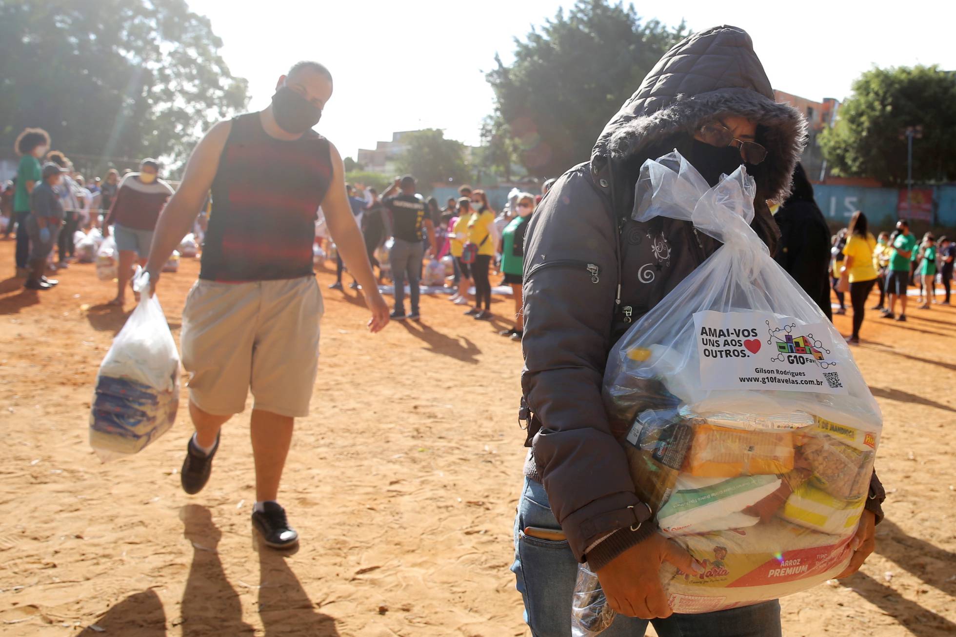 Pessoas carregam sacos de plástico com alimentos para serem distribuídos.