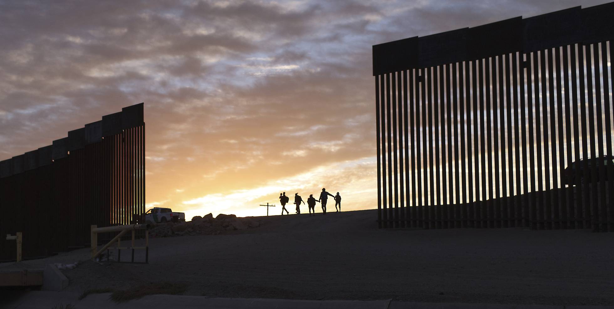 Un par de familias migrantes provenientes de Brasil pasan por un hueco del muro fronterizo para alcanzar Estados Unidos tras cruzar México, en Yuma, Arizona, EE UU.