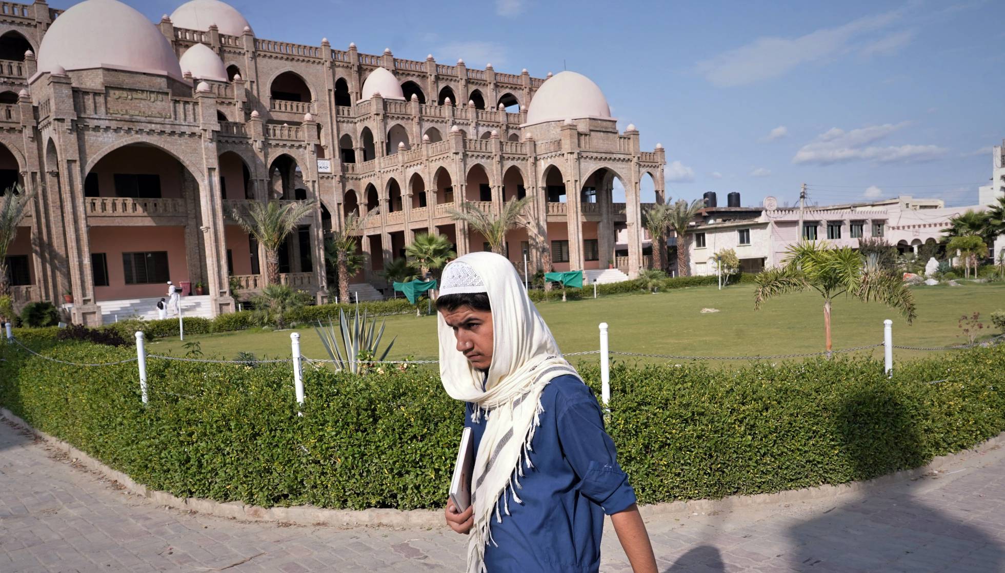 Un alumno pasa camino de clase delante del edificio principal de la Madrasa Haqqanía en Akora Khattak (Pakistán), una famosa escuela coránica con 4.000 alumnos por la que han pasado importantes líderes talibanes, algunos de ellos en el actual gobierno de Kabul.