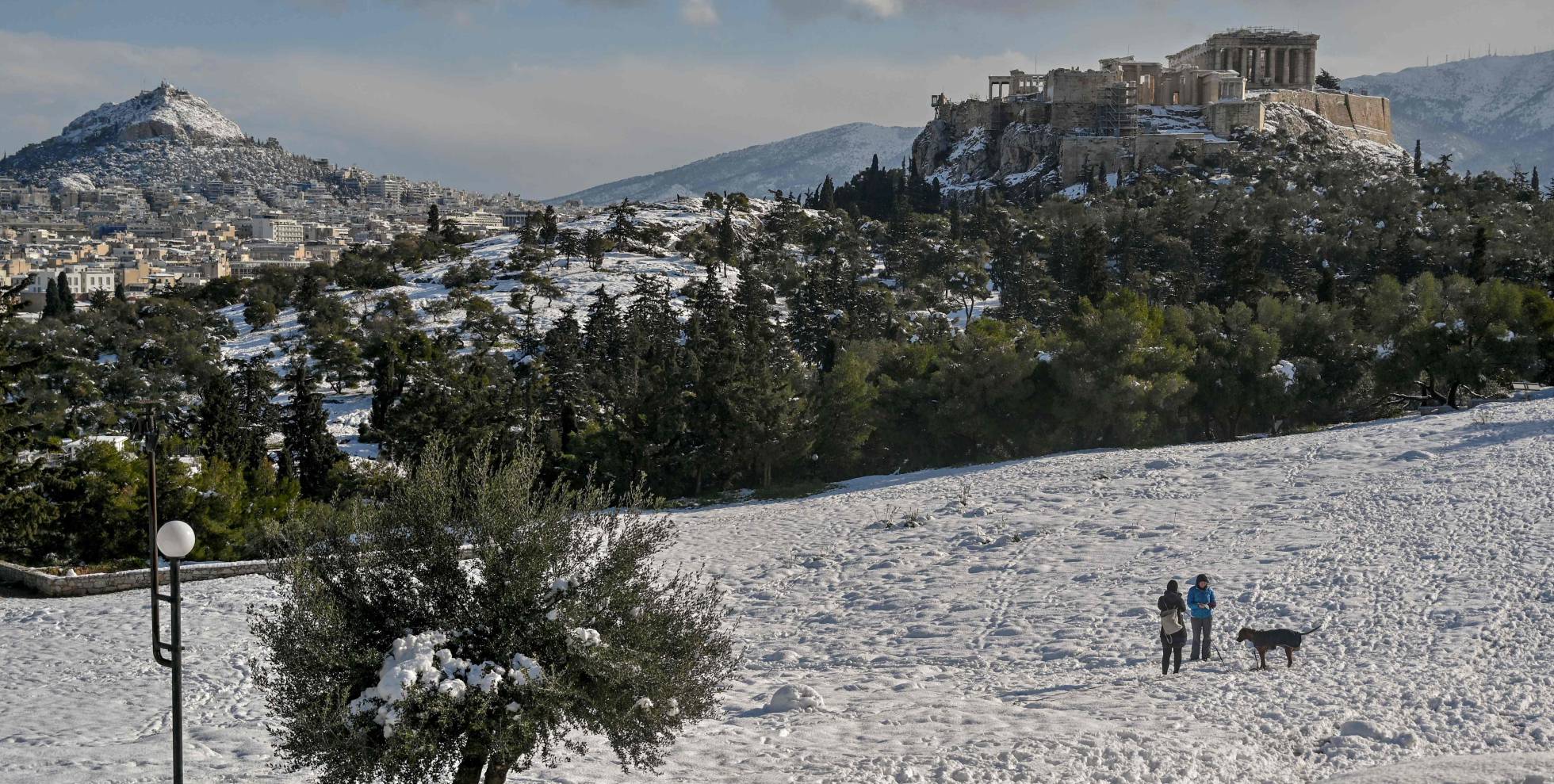 Gente que camina en la colina Pnyx cubierta de nieve en Atenas después de una tormenta de nieve el 25 de enero de 2022. Grecia amplió el feriado general hasta el 26 de enero, para evitar movimientos de personas ya que Grecia vive un frente frío con fuertes nevadas y temperaturas muy bajas.