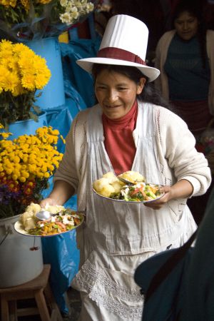 Una mujer sirviendo comida en un mercado de Cuzco.