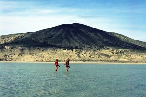 Una pareja cruza la laguna natural que la marea suele formas en la playa de Sotavento de Jandía, en Fuerteventura.