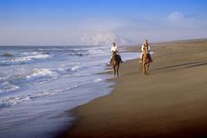 Un paseo a caballo por la playa de Sotogrande, con la roca de Gibraltar al fondo.