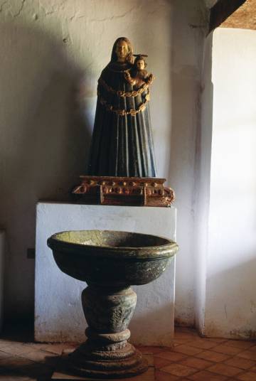 Pila bautismal y talla de la Virgen de Loreto (del siglo XVII) en el museo diocesano de San Ignacio Guazú.