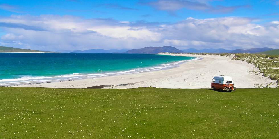 Una furgoneta camper frente a una playa de la isla de Bernerary, en Escocia.
