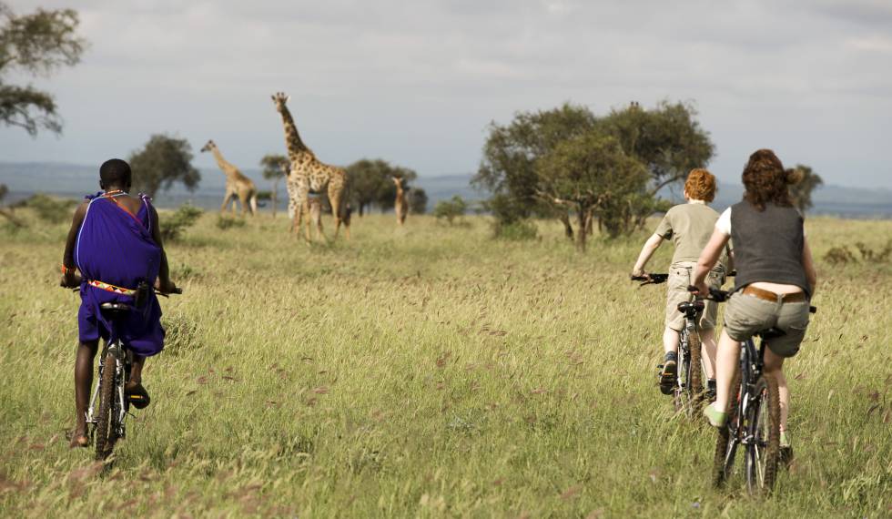 Un masai guía a una familia en una excursión en bici por en el parque nacional de Chyulu Hills (Kenia).