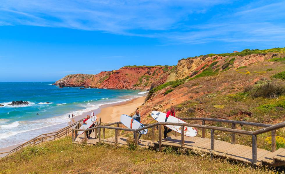 Surfistas en la pasarela de acceso a la playa de Amado, en la región del Algarve.