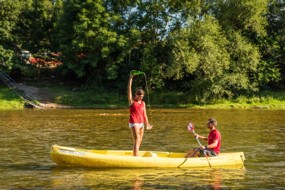 Una joven escancia un culín de sidra en una canoa a orillas del Sella