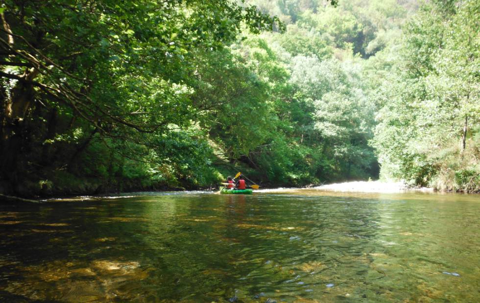 Dos chicos recorren las tranquilas aguas el río Polea sobre una canoa