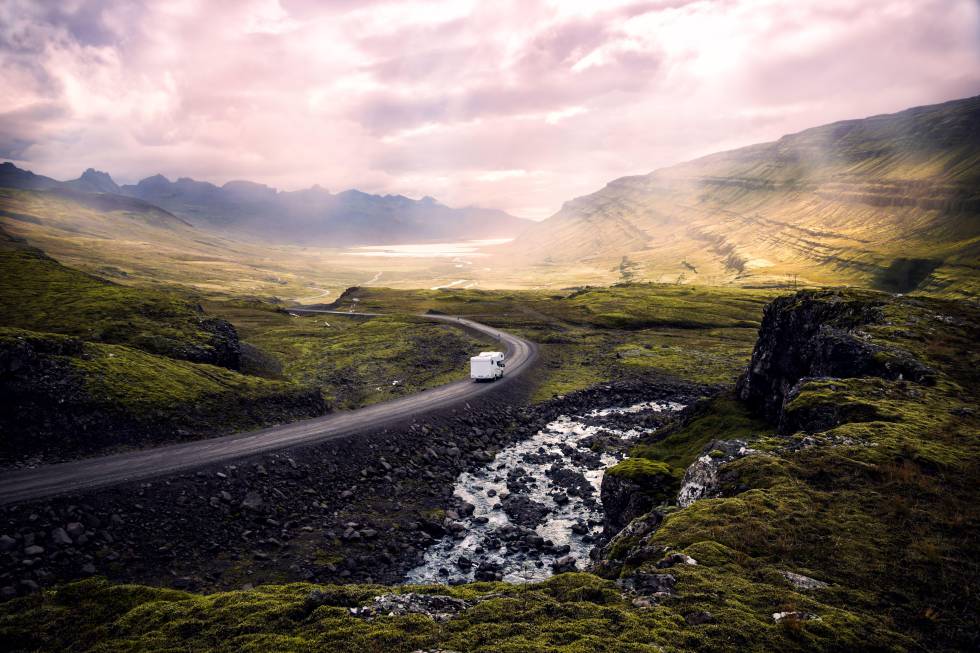 Una furgoneta ‘camper’ circula por una sinuosa carretera de Islandia.