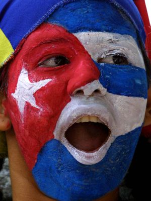 Una mujer con la cara pintada de la bandera cubana frente a la embajada de Cuba en Venezuela.