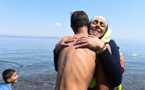 Un jove migrant sirià s'abraça a una companya de viatge quan desembarquen.