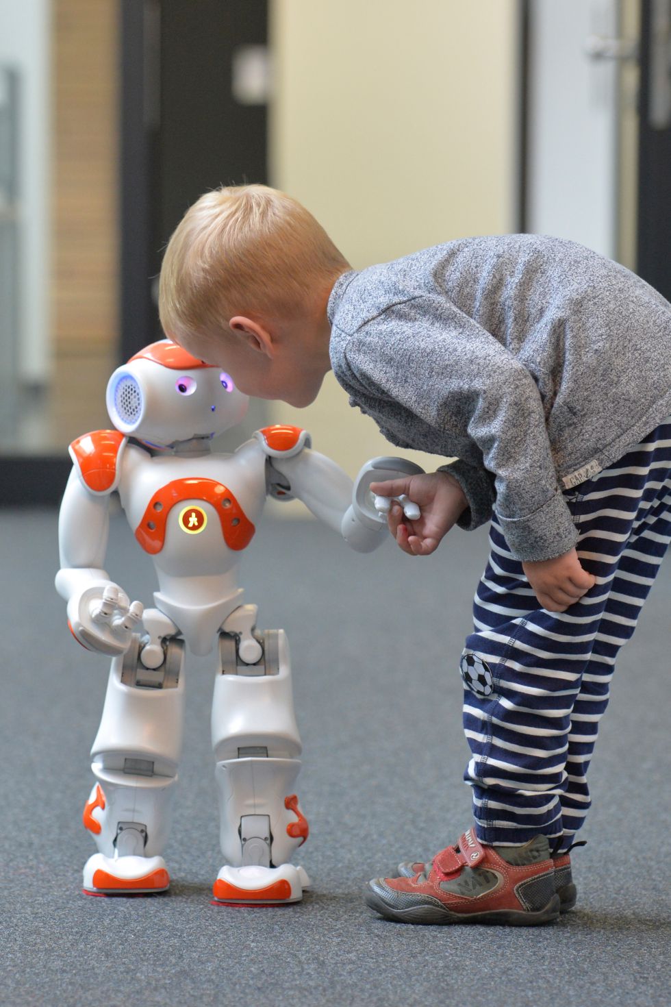 Un niño intenta comunicarse con el robot Neo.