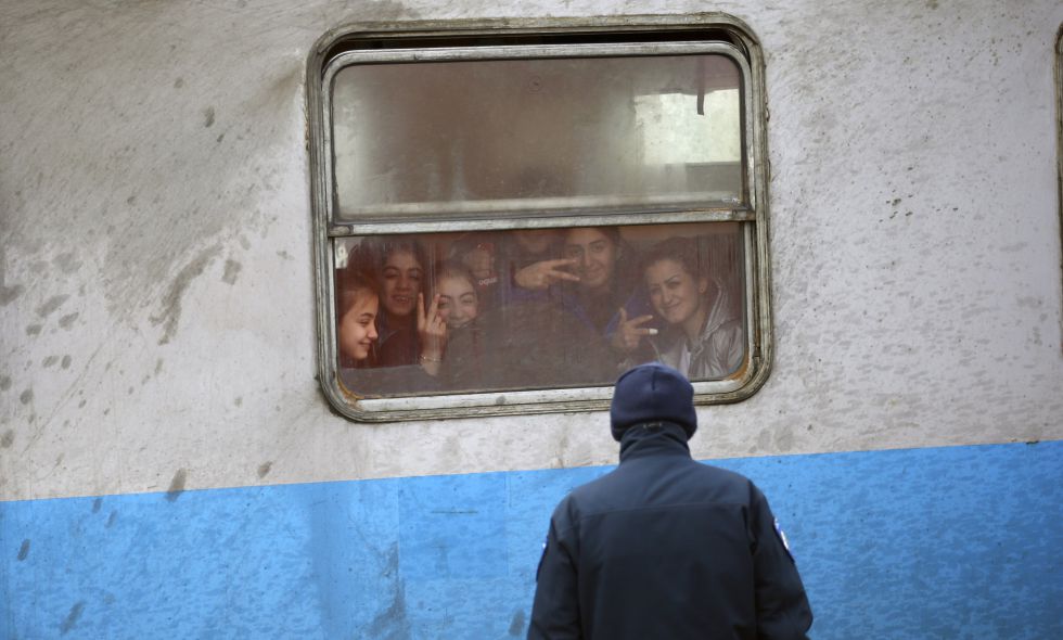 Un policía croata frente a un grupo de inmigrantes en un tren, este viernes cerca de la frontera con Serbia.