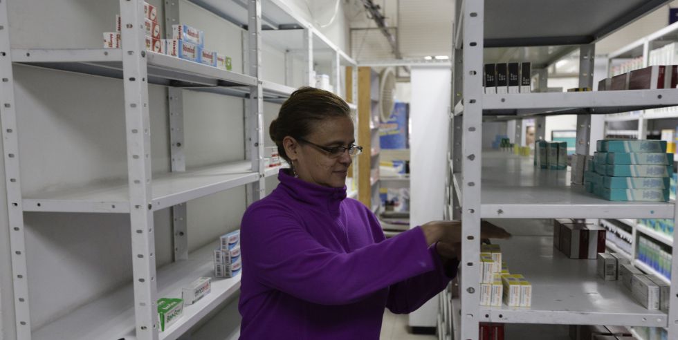 Una empleada de una farmacia toma medicinas de una estantería en Caracas.