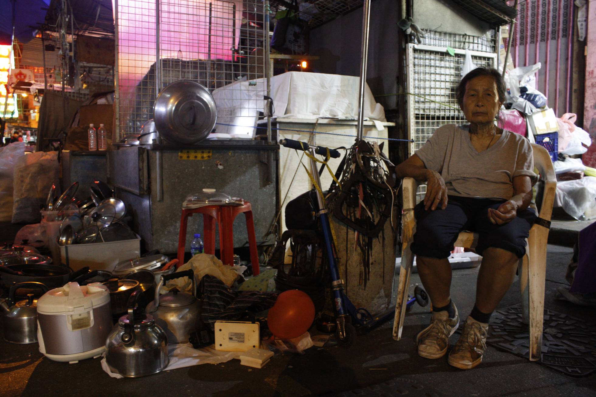 A senhora Chan, de 79 anos, em seu posto ilegal, onde também vive, no bairro de Sham Shui Po. A senhora Chan, de 79 anos, em seu posto ilegal, onde também vive, no bairro de Sham Shui Po.