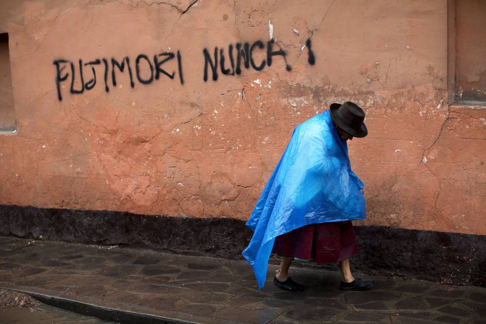Una mujer indígena camina junto a un graffiti en contra de Fujimori.