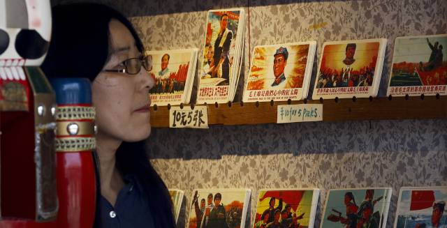 Una mujer observa iconos de la Revolución Cultural.