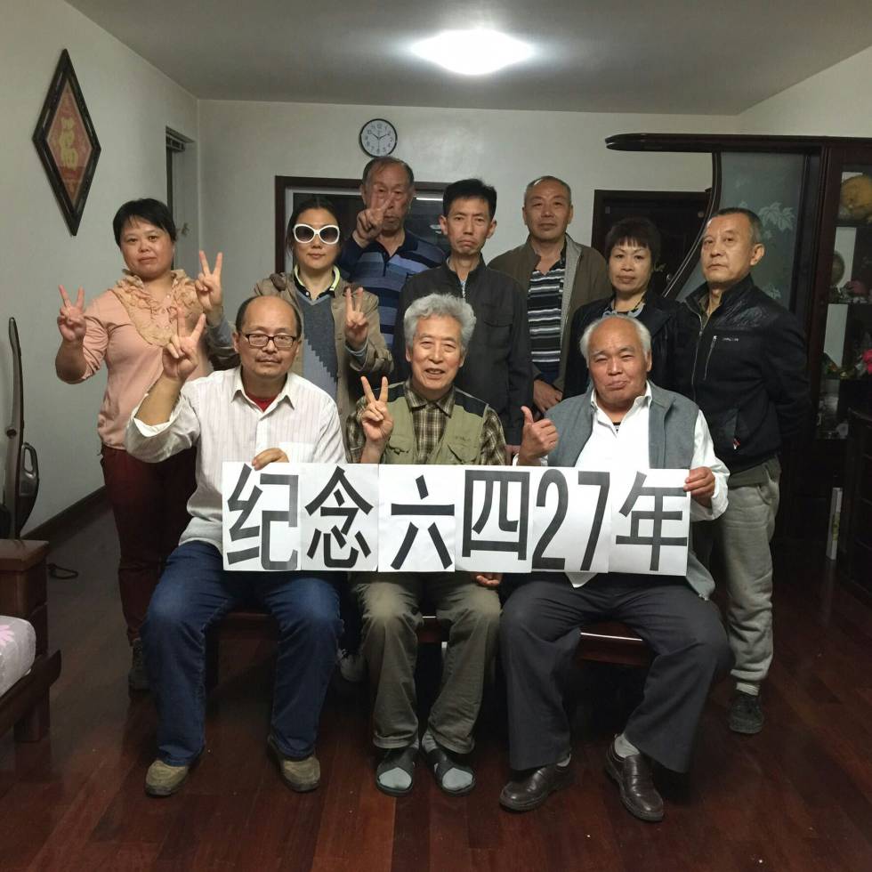 Sun Wenguang, sentado en el centro, junto a sus amigos en el homenaje que realizó en su casa. En la pancarta se puede leer: 