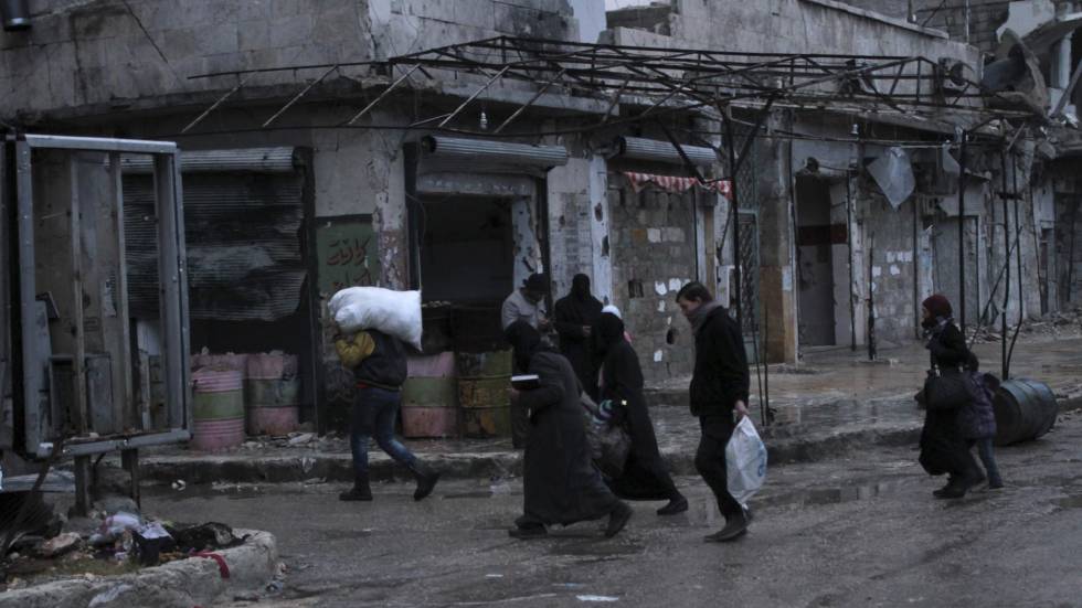 Várias pessoas carregam seus pertences no bairro de al-Mashad, zona controlada pelos rebeldes em Aleppo (Síria), em 14 de dezembro.