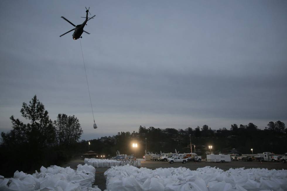 Un helicóptero lleva un saco de rocas para depositarlo en la zona dañada.