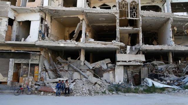 Niños sirios sentados en un edificio destrozado en la ciudad rebelde de Erbin, a las afueras de Damasco.
