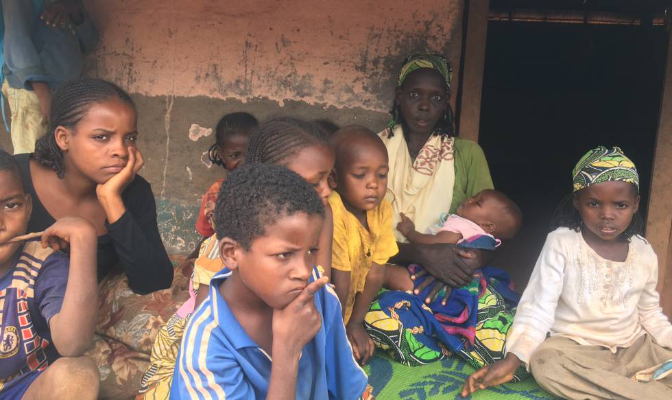 Ousman Kaltoumi, con uno de sus hijos en brazos, ante la cabaña en la que vive en el campo de Timangolo (Camerún).