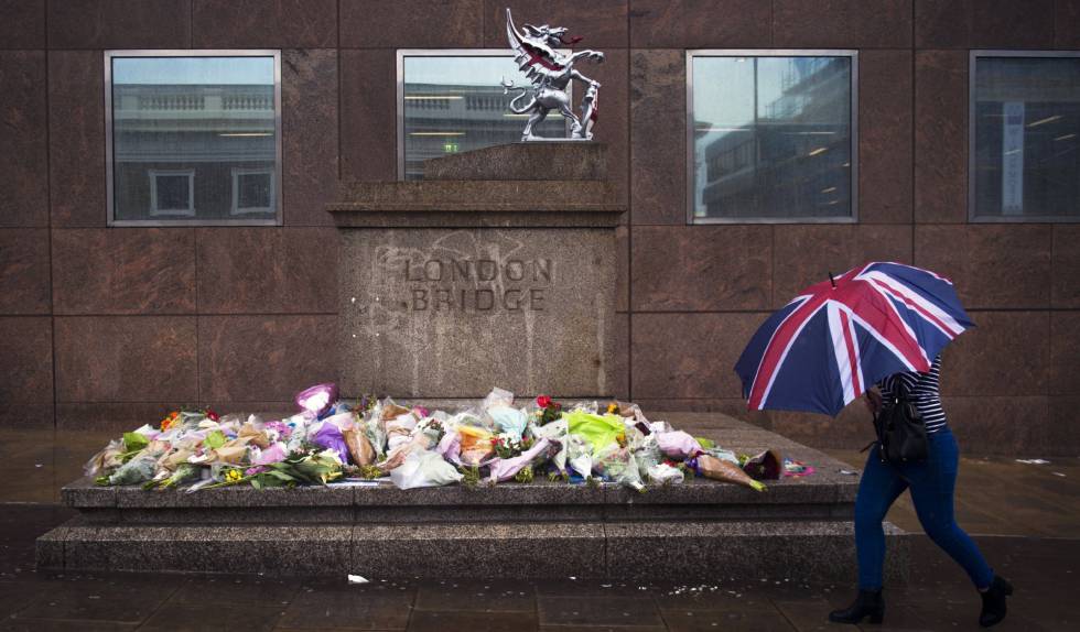 Una mujer pasa delante de varios ramos de flores dejados en memoria de las víctimas del atentado del sábado en el Puente de Londres.