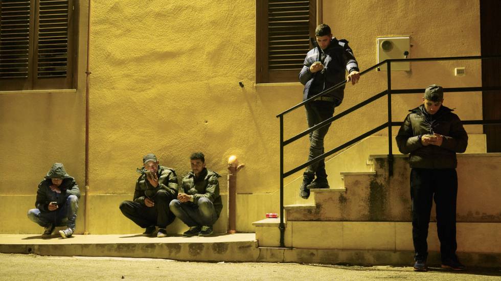 Varios inmigrantes tunecinos se conectan a la red inalámbrica de la iglesia de Lampedusa para hablar con sus familiares.