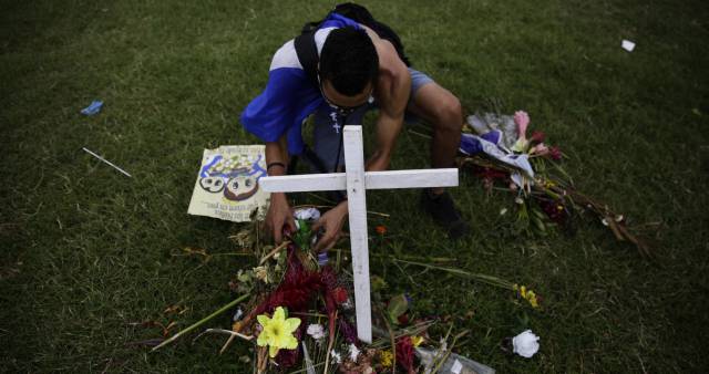 Un hombre deposita ofrendas en una cruz.