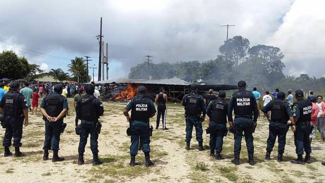 Agentes de policía vigilan el lugar donde manifestantes han quemado tiendas de campaña donde dormían inmigrantes venezolanos.