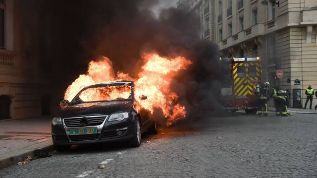 Un coche arde en París cerca del Arco del Triunfo.
